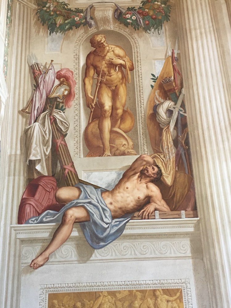 The reclining figure appears exhausted. Possibly after a battle, helmet, spears and body armour are depicted behind the reclining man.