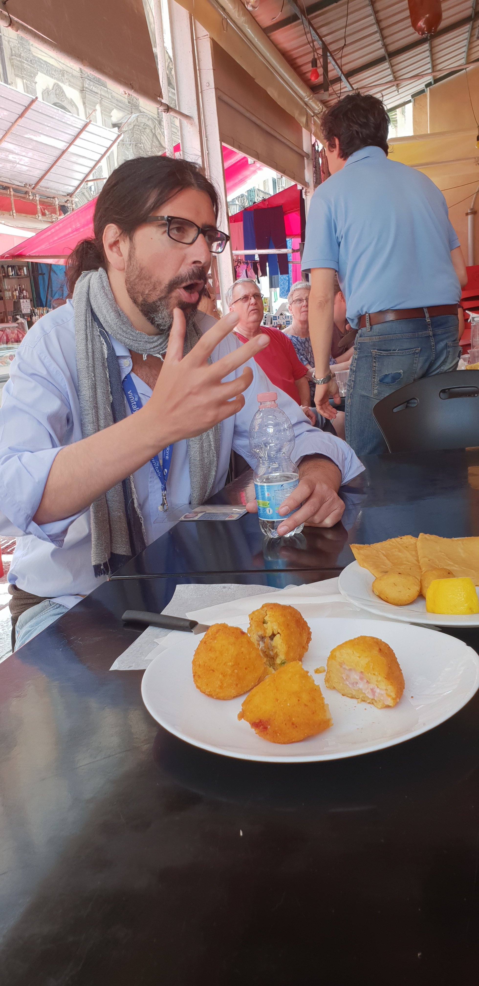 Giorgio explains the respective virtues of arancini - street market tour, Palermo, Sicily