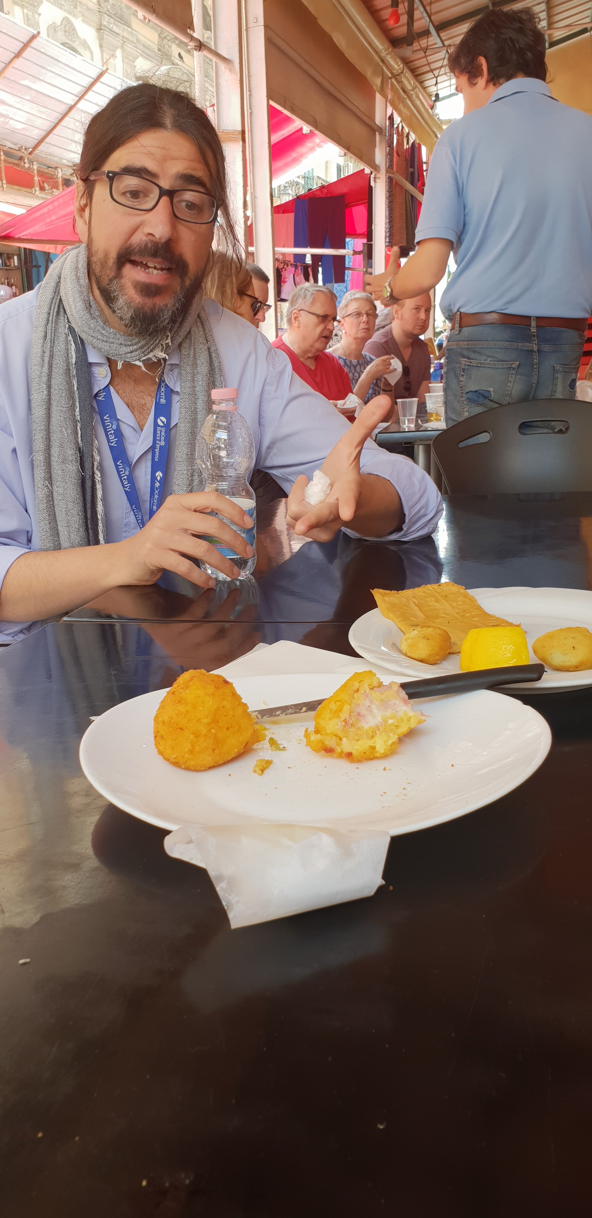 Giorgio explains the respective virtues of arancini - street market tour, Palermo, Sicily